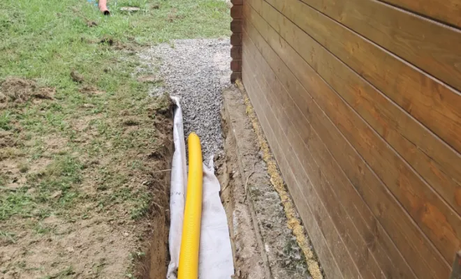 Pose du drain, géotextile et remblaiement en cailloux.