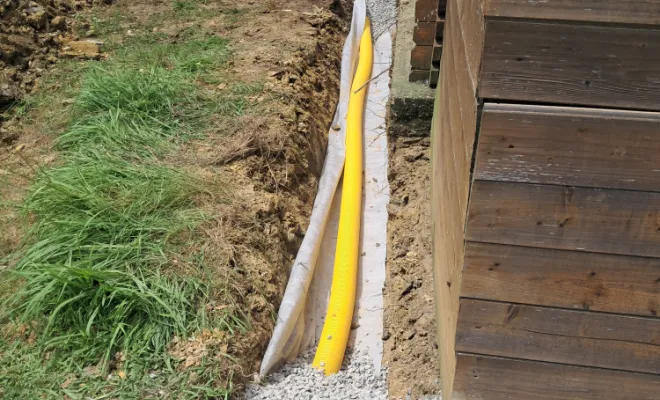 Pose du drain, géotextile et remblaiement en cailloux.